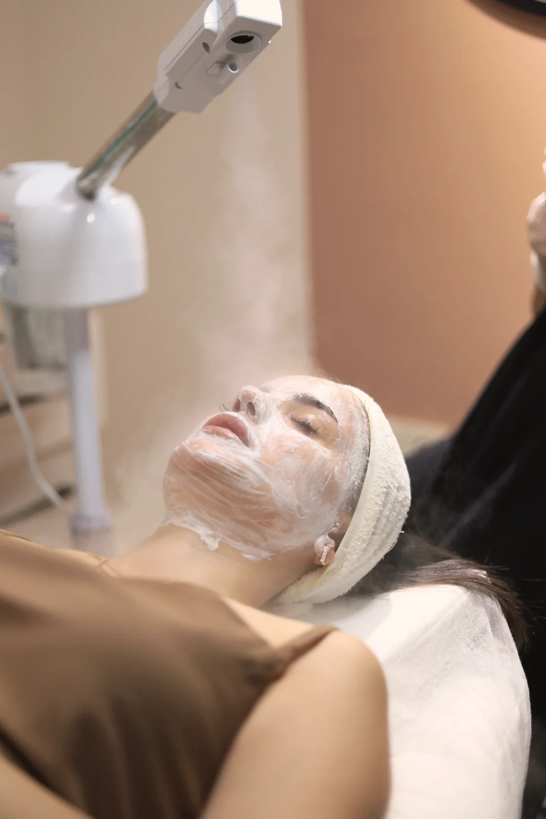 Pele recebendo vapor durante a limpeza de pele, com faixa no cabelo